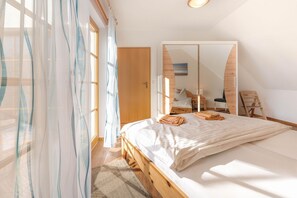 Ein Schlafzimmer mit einem hölzernen Bett, einem großen Spiegel und durchsichtigen Vorhängen.