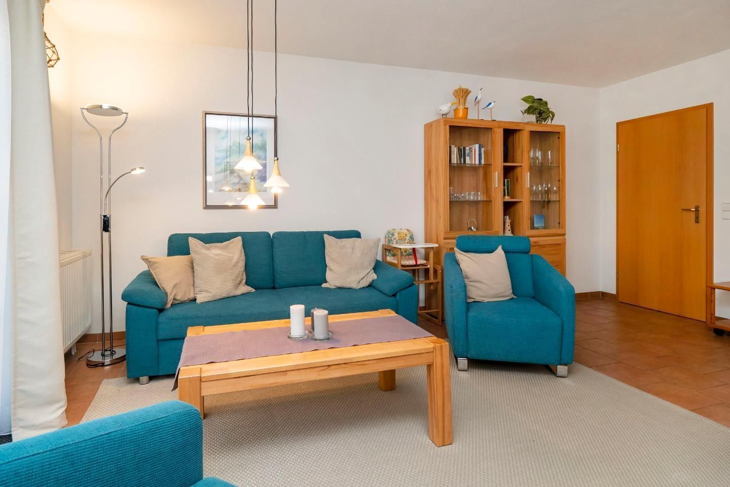 A living room with teal sofas, a wooden coffee table, and a bookshelf.