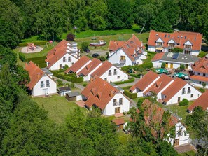 Um bairro residencial com casas brancas, telhados vermelhos e um parquinho.