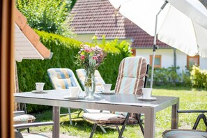 Un espace extérieur aménagé avec une table, des chaises et un vase de fleurs.