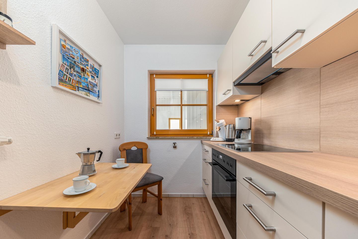 Une cuisine de taille réduite avec une table en bois, une machine à café et une fenêtre.
