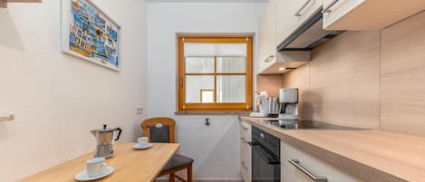 Une cuisine de taille réduite avec une table en bois, une machine à café et une fenêtre.