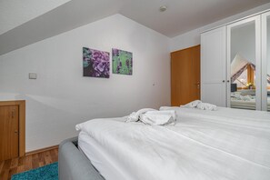 A bedroom with a bed, a wardrobe, and two wall-mounted flower paintings.