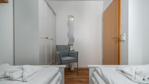 A hotel room with two beds, a chair, and a wardrobe. - Terraced house Seehund in the Freesenbruch vacation park: comfort for families in Zingst - (Zingst)