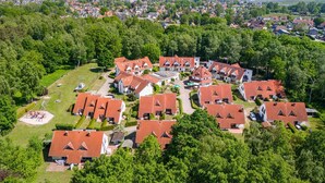 A residential area with multiple houses, a playground, and a large building with a red roof. - Terraced house Seehund in the Freesenbruch vacation park: comfort for families in Zingst - (Zingst)
