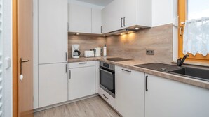 A modern kitchen with white cabinets, a wooden countertop, a built-in oven, and a sink. - Terraced house in Zingst with terrace, garden view and heated indoor pool - (Zingst)