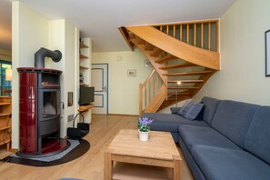 Ein Wohnzimmer mit Kaminofen, einer Couch, einem Couchtisch und einer Treppe.