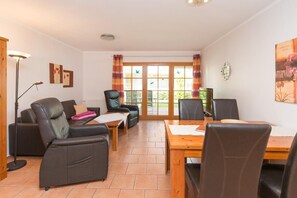 Una sala de estar acogedora con un sofá, sillas, una mesa de comedor y un televisor.