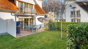 A two-story house with a balcony, a patio with outdoor furniture, and a well-maintained lawn. - Spacious Möwennest vacation apartment with terrace, garden view and pool in Zingst (Zingst)