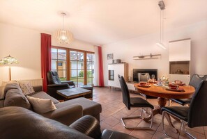 Una sala de estar moderna con un sofá, una mesa de comedor para cuatro personas y un televisor.