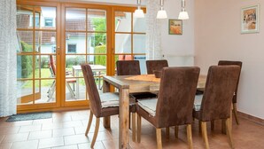 A dining area with a wooden table and six chairs, a sliding glass door leading to a garden, and a radiator on the wall.