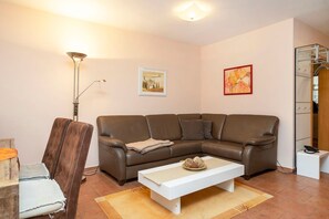 Un salon avec un canapé en cuir marron, une table basse blanche, un lampadaire et un tableau accroché au mur.