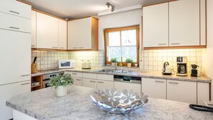 Een moderne keuken met witte kasten, een granieten aanrechtblad, een vaatwasser, een magnetron, een broodrooster en een koffiezetapparaat.