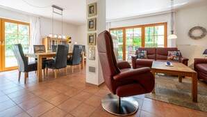 Een ruime woonkamer met een eettafel, stoelen, een bank en een salontafel.