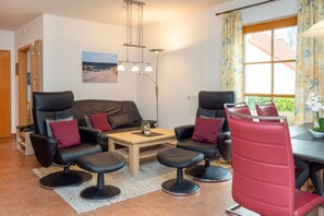 A living room with a sofa, two armchairs, a coffee table, and a dining table with chairs. - Terraced house Seestern: Family-friendly with terrace and garden in Zingst - (Zingst)