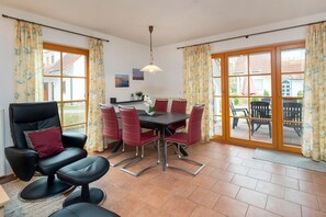 A dining area with a table and chairs, a sofa, and a view of the outside. - Terraced house Seestern: Family-friendly with terrace and garden in Zingst - (Zingst)