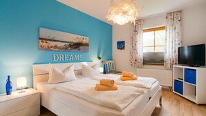 A bedroom with two beds, a TV, and a painting on the wall. - Comfortable vacation apartment with terrace, garden view and heated pool in Zingst (Zingst)