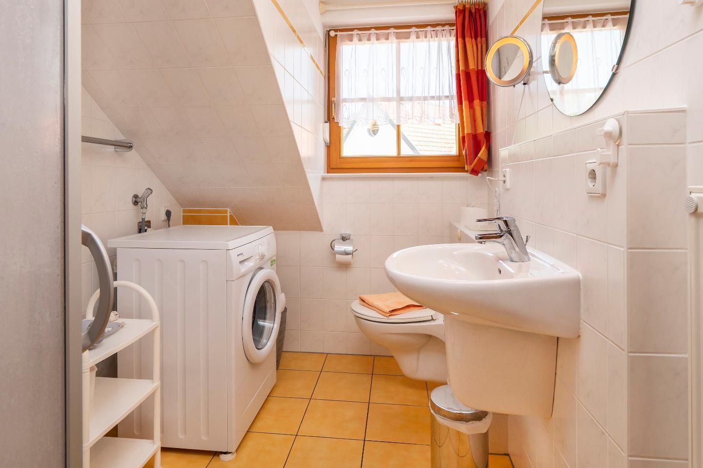 A compact bathroom with a washing machine, a sink, and a toilet.