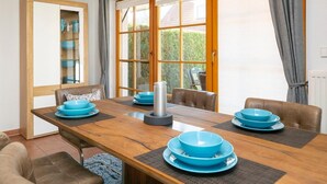 A dining area with a wooden table set for six, surrounded by leather chairs. - Comfortable terraced house with terrace and garden in the Freesenbruch vacation park - (Zingst)