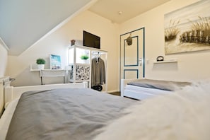 A bedroom with a bed, a wardrobe, a desk, and a painting on the wall.