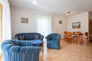 En stue med sofa, to lænestole, et sofabord og et spiseområde med bord og stole.