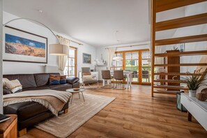 A modern living room with a leather sofa, a coffee table, and a dining area with chairs. - Comfortable terraced house with terrace in the Freesenbruch vacation park near the sandy beach (Zingst)