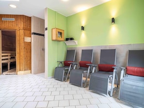 Un sauna con bancos de madera, una puerta de madera y un calentador fijado a la pared.