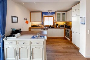 Una cocina compacta con armarios blancos, una encimera de madera y un horno empotrado.