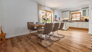 A modern kitchen with white cabinets, a wooden countertop, and a dining area with a table and chairs.