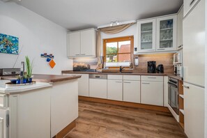 Een moderne keuken met witte kasten, een houten aanrechtblad en een geïntegreerde vaatwasser.