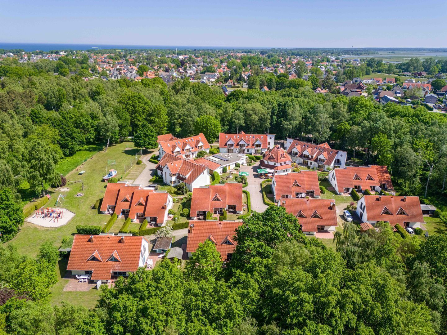A residential area with multiple houses, a playground, and a large building with a red roof.