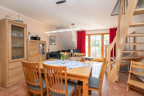 Un rincón comedor acogedor con una mesa y sillas de madera, un aparador con puertas de cristal y una escalera.