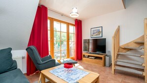 Un salon avec un canapé, une table basse, un téléviseur et un escalier.