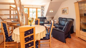 Una sala de estar acogedora con comedor, una escalera y vistas al exterior.