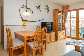Un comedor con una mesa de madera, sillas y un televisor.