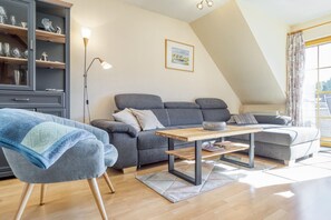 Ein modernes Wohnzimmer mit einem grauen Sofa, einem Holztisch und einem blauen Sessel.
