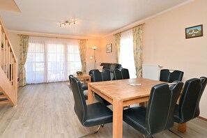 Uma área de refeições com uma mesa de madeira e cadeiras pretas, uma escada e um radiador.
