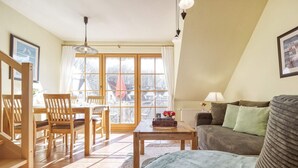 Una sala de estar acogedora con comedor, un sofá y una mesa con un jarrón de flores.