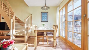 Un comedor con una mesa de madera, sillas, un televisor y una escalera.