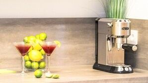 Eine Küchenarbeitsplatte mit einer Kaffeemaschine, zwei Martini-Gläsern und Limetten.