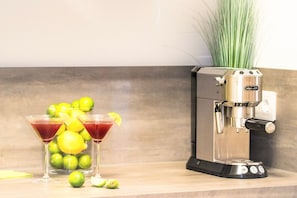 Eine Küchenarbeitsplatte mit einer Kaffeemaschine, zwei Martini-Gläsern und Limetten.