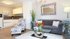 Ein modernes Wohnzimmer mit Glastisch, gemustertem Sessel, grauem Sofa und dekorativen Vasen.