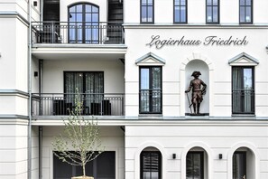 A building with the sign "Logierhaus Friedrich" and a statue of a historical figure on the facade. - Modern apartment with balcony and limited sea view in Zingst - (Zingst)