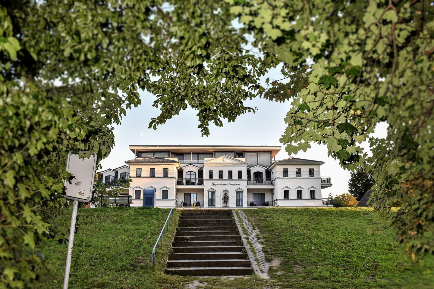 A multi-story hotel with a central staircase, surrounded by lush greenery.