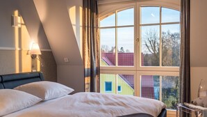 Un dormitorio con un ventanal grande, una cama y una mesita de noche.