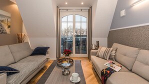 Una sala de estar moderna con dos sofás, una mesa de centro y un ventanal con cortinas.
