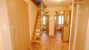 A narrow hallway with a wooden staircase, a door with a handle, and a radiator on the wall. - Haus Sabine - Upper floor - Bright, large upper floor apartment in a quiet location! (Zingst)
