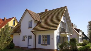 A two-story house with a balcony, a door with a window, and a small garden area. - Haus Sabine - Upper floor - Bright, large upper floor apartment in a quiet location! (Zingst)
