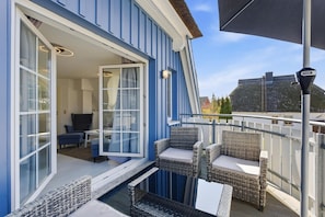 A balcony with wicker furniture, a glass door leading to an interior room, and a clear view of a building in the background. - Rosenberg-Siedlung 21a/2 - Bright and friendly dream vacation apartment for the (Zingst)