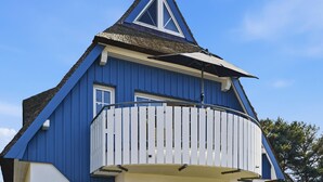 Un bâtiment bleu avec un balcon blanc et un toit triangulaire.